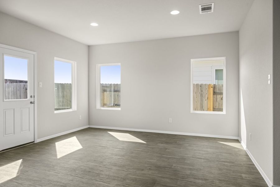 Image of home dining area with wood-look flooring, white walls, and windows on wall and door to backyard
