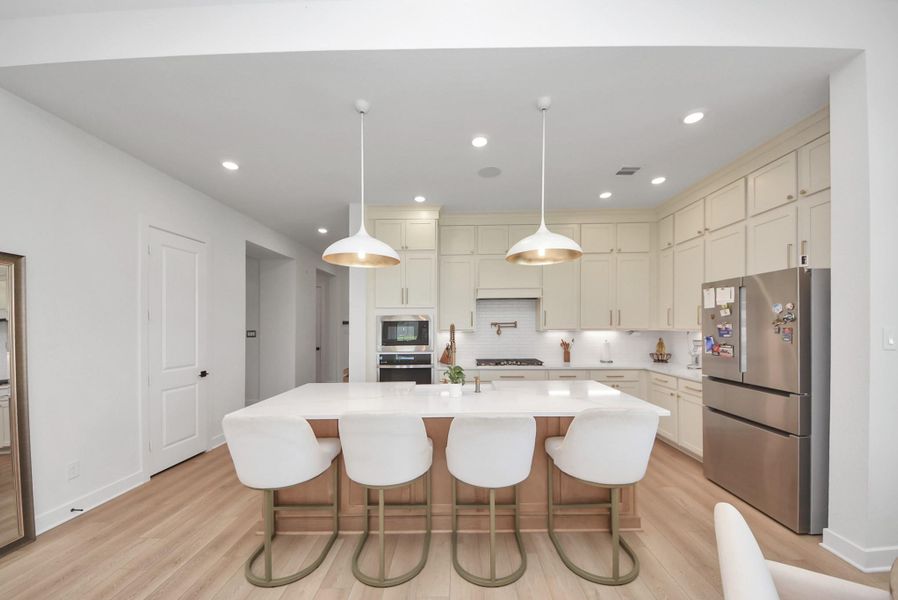 Modern kitchen with sleek stainless steel appliances, ample cabinetry, and a large island featuring elegant pendant lighting, perfect for entertaining.