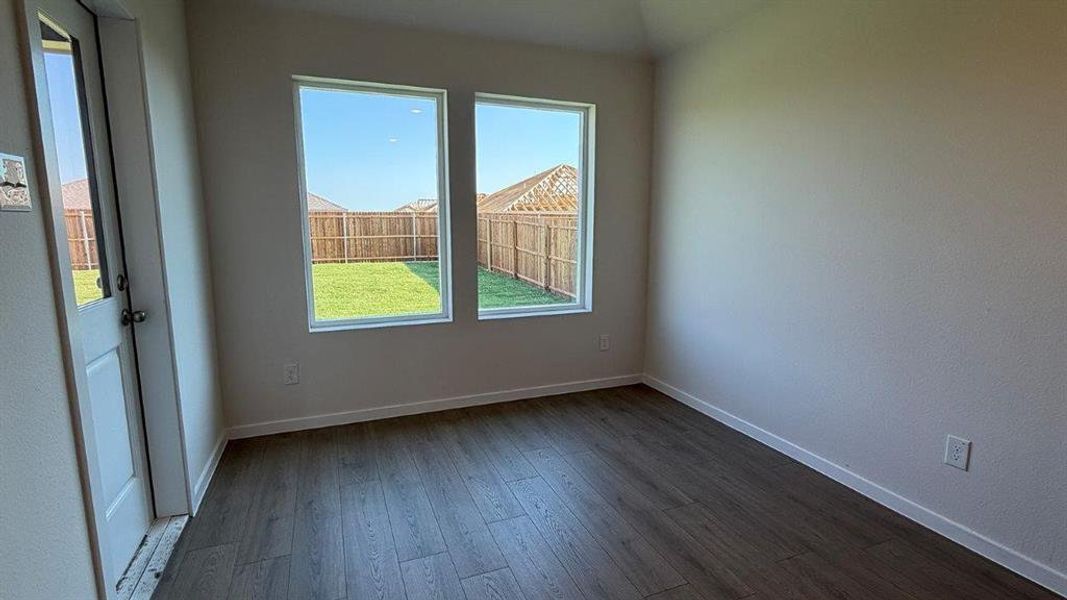 Room featuring wood-finish flooring, neutral wall tones, and white trim Room featuring wood-finish flooring, neutral wall tones, and white trim