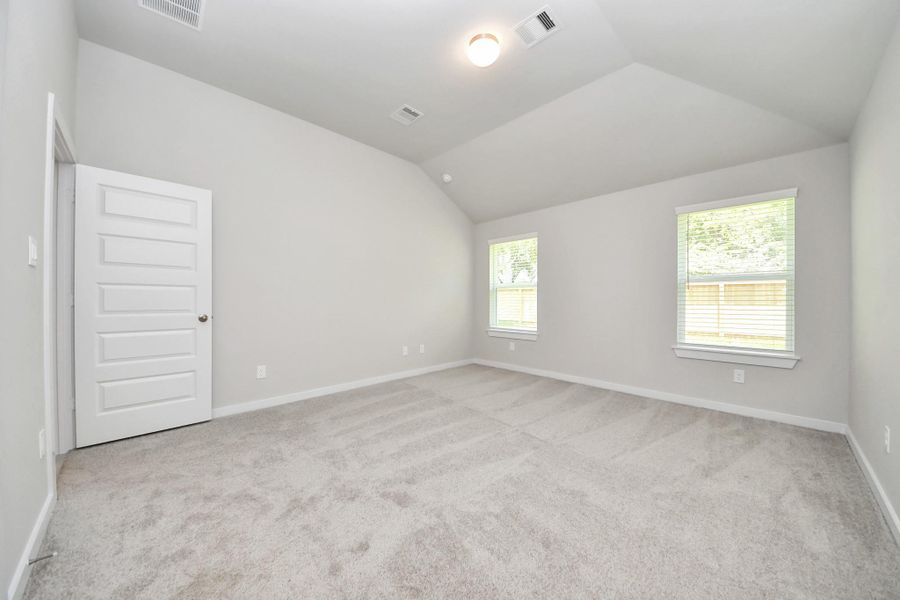 Escape to tranquility in this spacious primary room, adorned with plush carpeting and bathed in the soothing hues of warm paint colors, creating a cozy retreat for relaxation. Sample photo of completed home with similar floor plan. Actual colors and selections may vary.