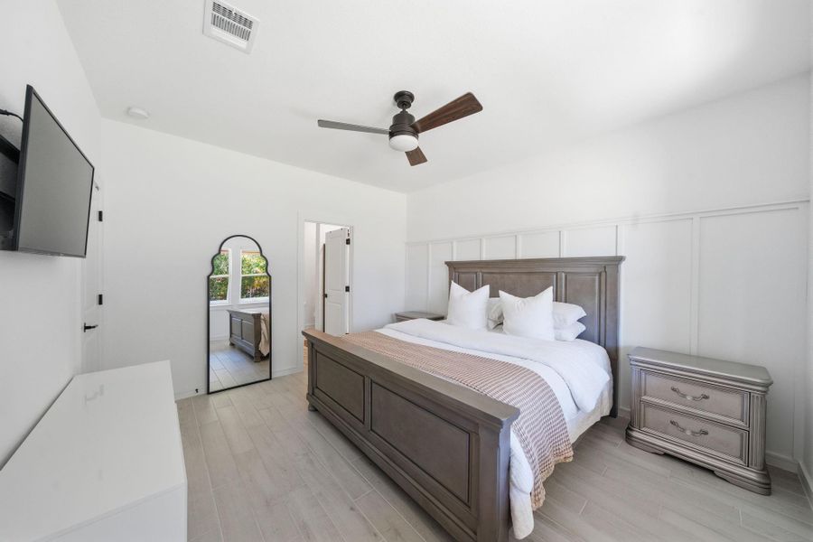 This bedroom features a modern design with  and a ceiling fan. Natural light streams in making this primary bedroom bright and inviting, perfect for relaxation.