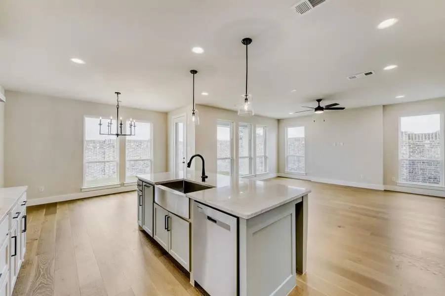 Spacious open-concept interior featuring light wood-finish flooring, recessed lighting, and ample natural light from multiple windows