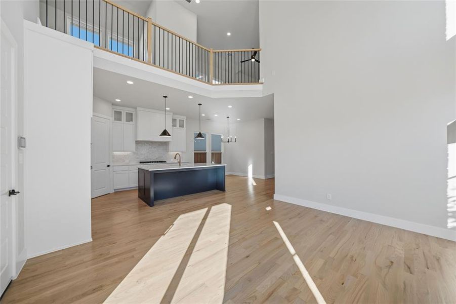 Unfurnished living room with light wood-style floors, a towering ceiling, and recessed lighting