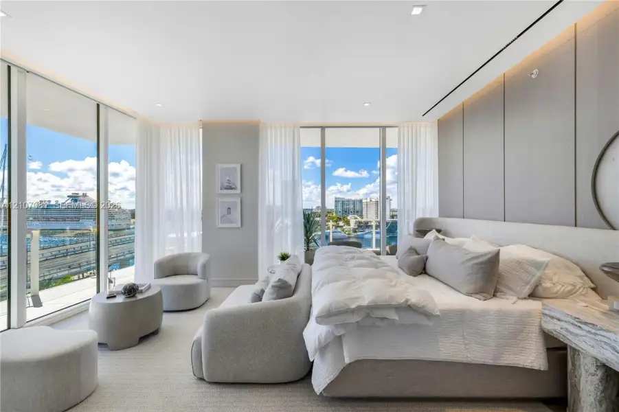 Floor-to-ceiling windows, large-format panel accent wall, recessed perimeter lighting, and neutral-tone flooring Floor-to-ceiling windows, large-format panel accent wall, recessed perimeter lighting, and neutral-tone flooring