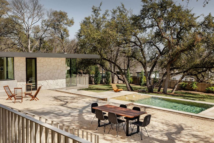 View from the covered porch out onto the resort-style terrace with separate pool and lounge area, and large, fully-fenced grassy yard. Plenty of space for relaxation, entertainment and play!