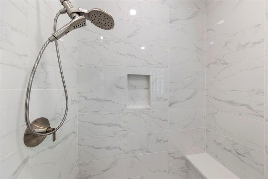 The shower is elegantly designed with floor-to-ceiling tile and includes a convenient ledge, providing both style and practicality for your daily routine.