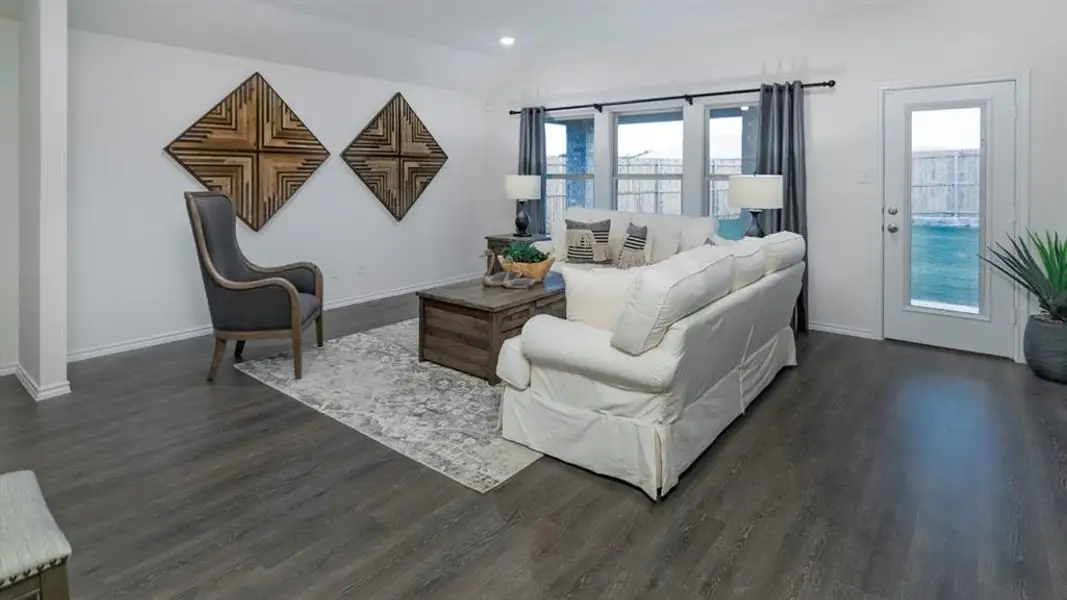 Open-concept living area featuring wood-finish flooring, white walls, and bright natural light from multiple windows