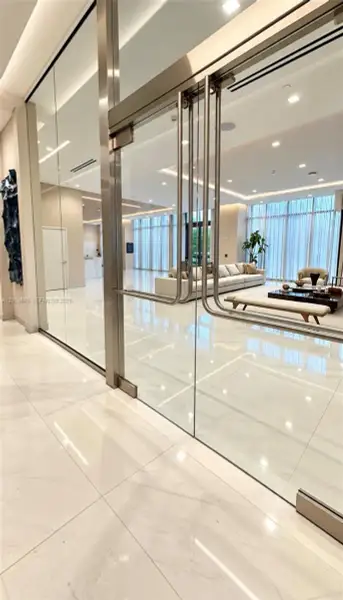Floor-to-ceiling glass partition featuring polished metal hardware, expansive ceramic tile flooring, recessed ceiling lighting, and full-height windows Floor-to-ceiling glass partition featuring polished metal hardware, expansive ceramic tile flooring, recessed ceiling lighting, and full-height windows