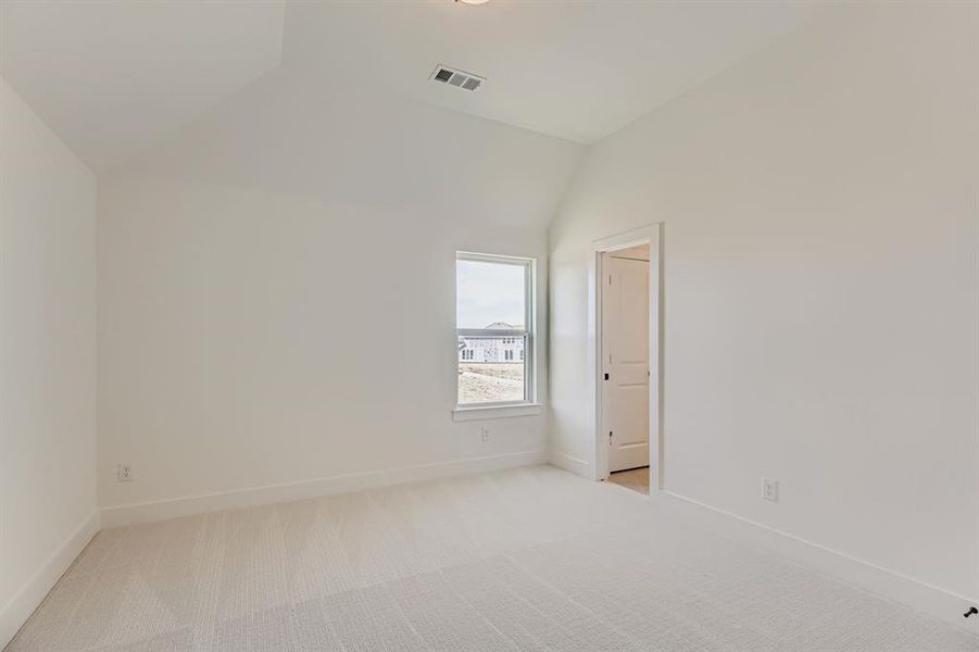 Spare room featuring carpet flooring and vaulted ceiling