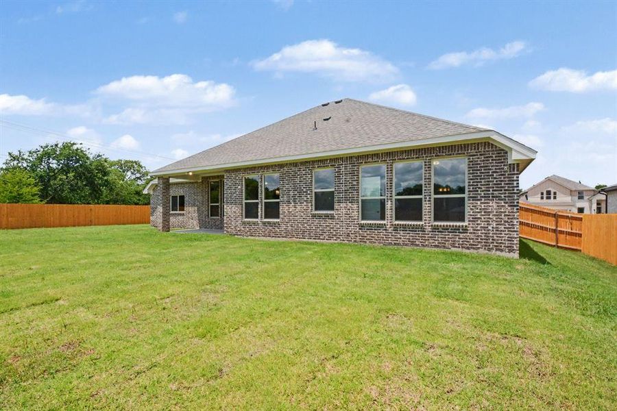 Expansive green lawn with a newly built brick exterior and a privacy fence Expansive green lawn with a newly built brick exterior and a privacy fence