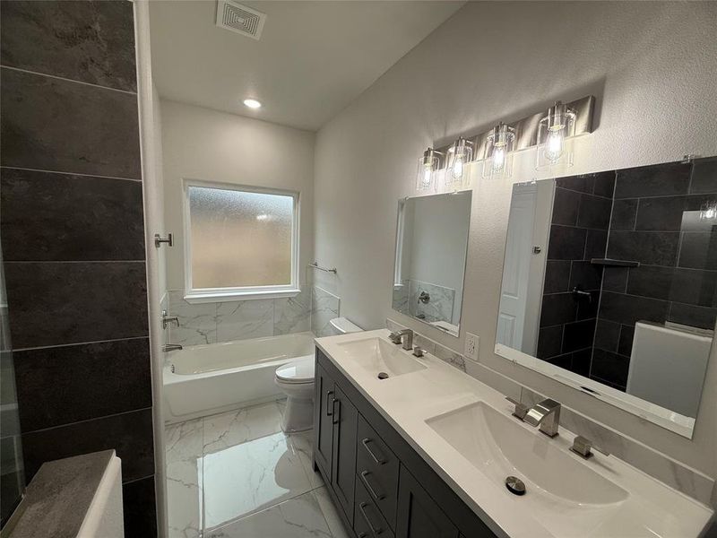 Full bathroom with vanity, toilet, and tiled shower / bath