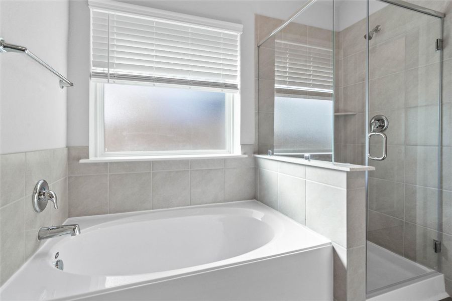Additional view of the primary bathroom showcases the soaking tub and walk-in shower with window allowing in natural lighting. Additional view of the primary bathroom showcases the soaking tub and walk-in shower with window allowing in natural lighting.