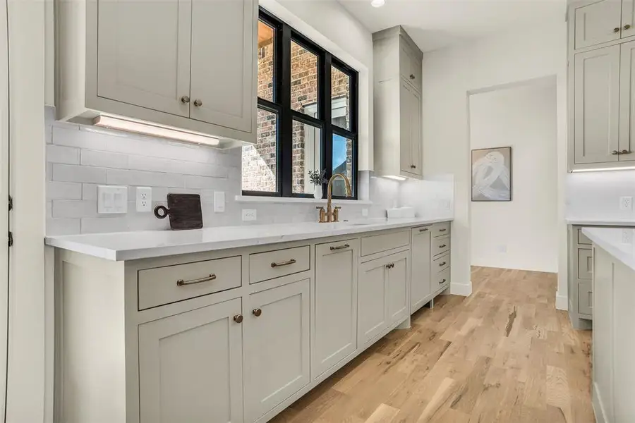 Kitchen featuring decorative backsplash, light wood-style floors, gray cabinetry, light stone counters, and recessed lighting