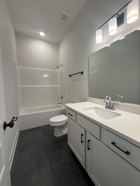 Full bath with vanity, shower / washtub combination, and dark tile patterned flooring