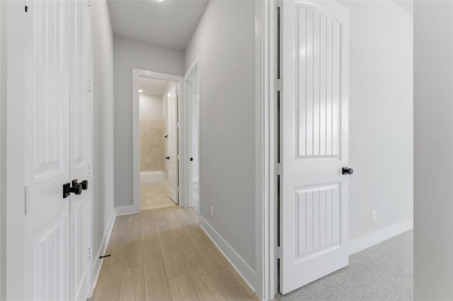 Hallway with light wood finished floors and recessed lighting