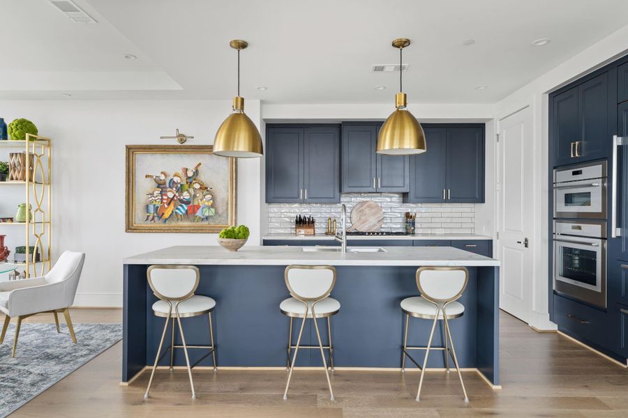 This modern kitchen features sleek navy cabinetry, a white stone countertop, and stylish gold pendant lighting. It includes stainless steel Thermador and Sub-Zero appliances and a central island with seating. The open layout and wooden floors add warmth and sophistication. This modern kitchen features sleek navy cabinetry, a white stone countertop, and stylish gold pendant lighting. It includes stainless steel Thermador and Sub-Zero appliances and a central island with seating. The open layout and wooden floors add warmth and sophistication.
