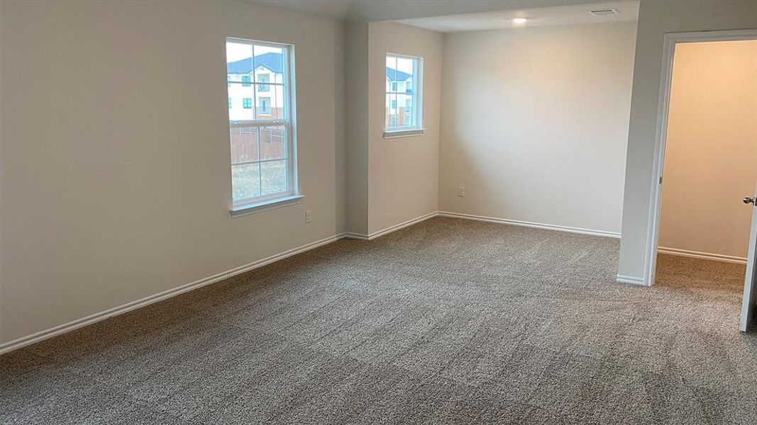 Empty room with light colored carpet and baseboards