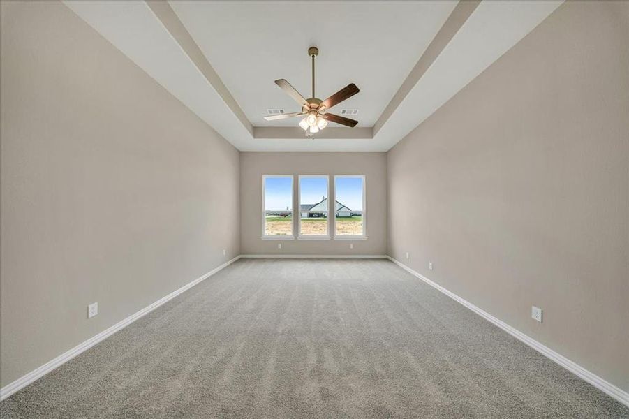 Unfurnished room with a raised ceiling, a ceiling fan, and light colored carpet Unfurnished room with a raised ceiling, a ceiling fan, and light colored carpet