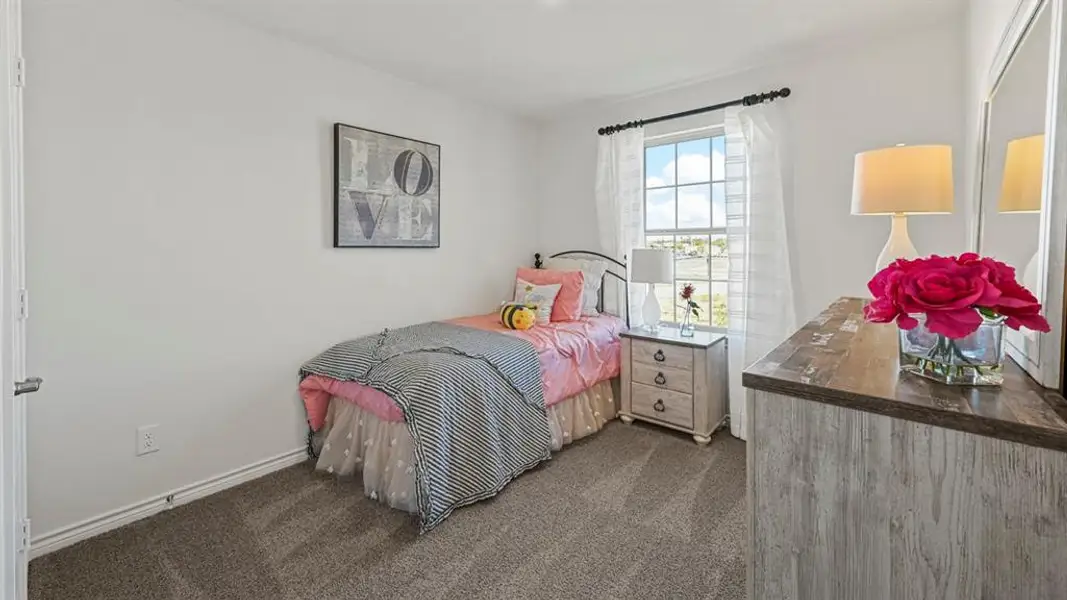 Bedroom featuring soft gray carpeting, white walls, and a multi-pane window with white sheers