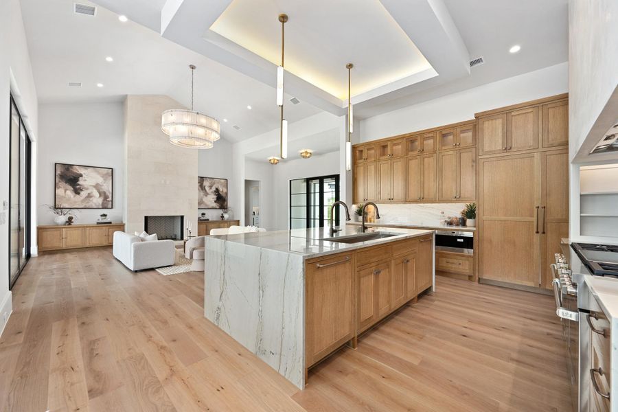 An open concept living area boasts a modern kitchen island with a waterfall countertop and 60" SubZero