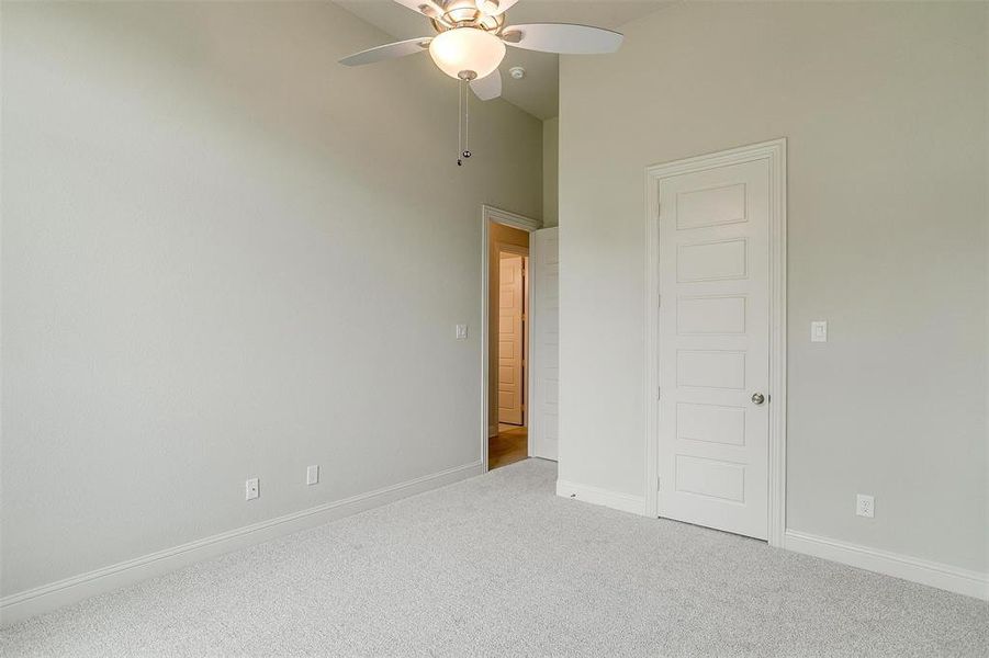 Unfurnished bedroom with ceiling fan, carpet, and high vaulted ceiling