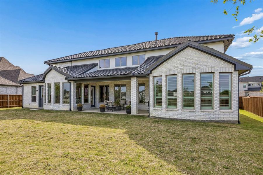 Back of property featuring a fenced backyard, a patio, brick siding, and a tiled roof