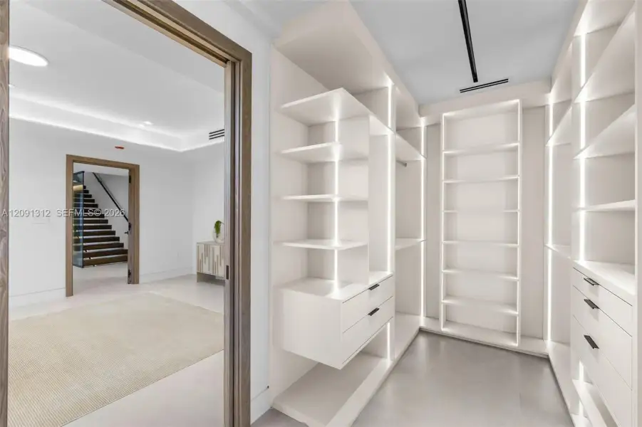 Custom walk-in closet featuring floor-to-ceiling built-in shelving, integrated vertical LED lighting, and drawer storage with matte black hardware Custom walk-in closet featuring floor-to-ceiling built-in shelving, integrated vertical LED lighting, and drawer storage with matte black hardware