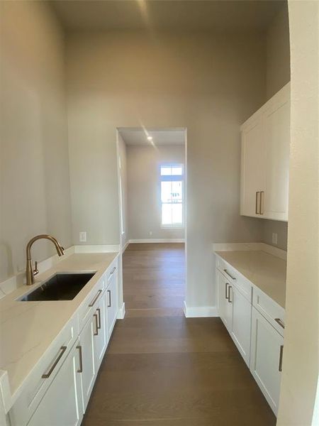Kitchen with white cabinetry, dark wood-style floors, light stone counters, and a peninsula