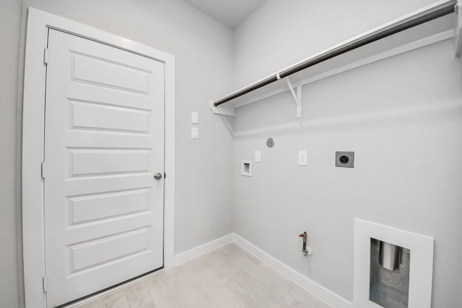 A perfect blend of functionality and comfort. Capture the essence of easy living with a first-floor laundry room, thoughtfully equipped with shelving for effortless organization. Both electric and gas connections available. Sample photo of completed home with similar floor plan. Actual colors and selections may vary.