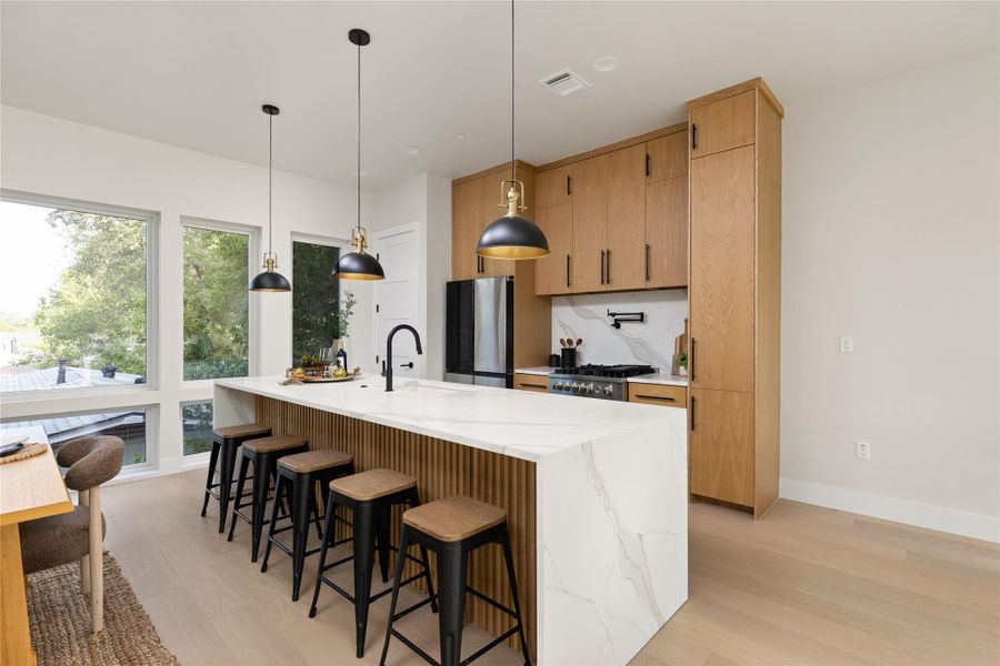 Warm wood cabinetry pairs with marble-look stone countertops in a modern kitchen design.