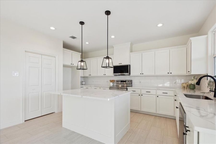 Kitchen featuring white cabinets, appliances with stainless steel finishes, a center island, and sink