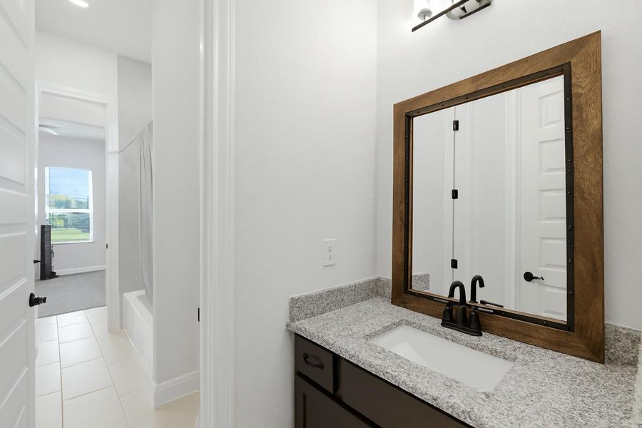 Granite counters complement the rich wood-framed mirror in this well-appointed bathroom vanity. Granite counters complement the rich wood-framed mirror in this well-appointed bathroom vanity.