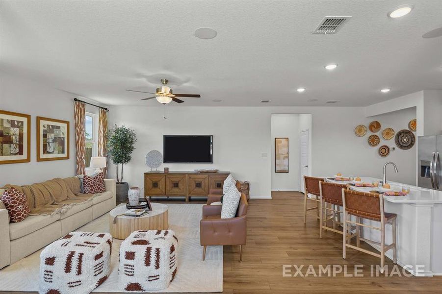 Living room featuring ceiling fan, a textured ceiling, and light wood-type flooring