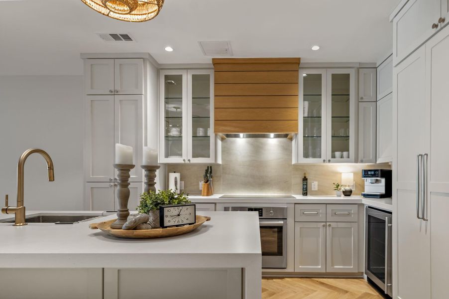 A well-lit kitchen with sleek countertops and herringbone hardwood flooring.