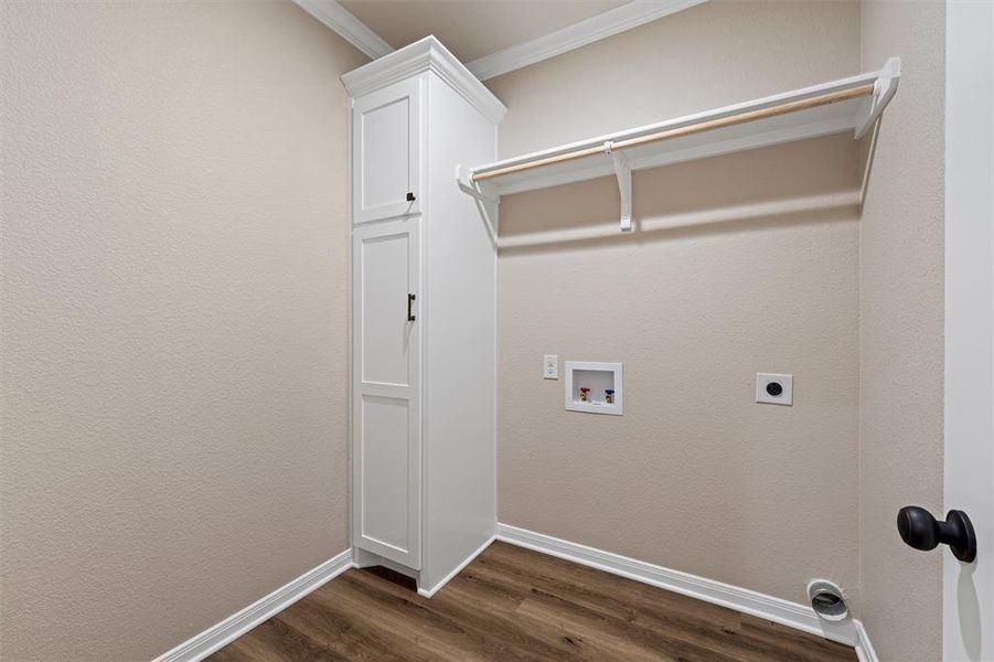 Washroom with hookup for an electric dryer, washer hookup, dark wood-style floors, ornamental molding, and cabinet space