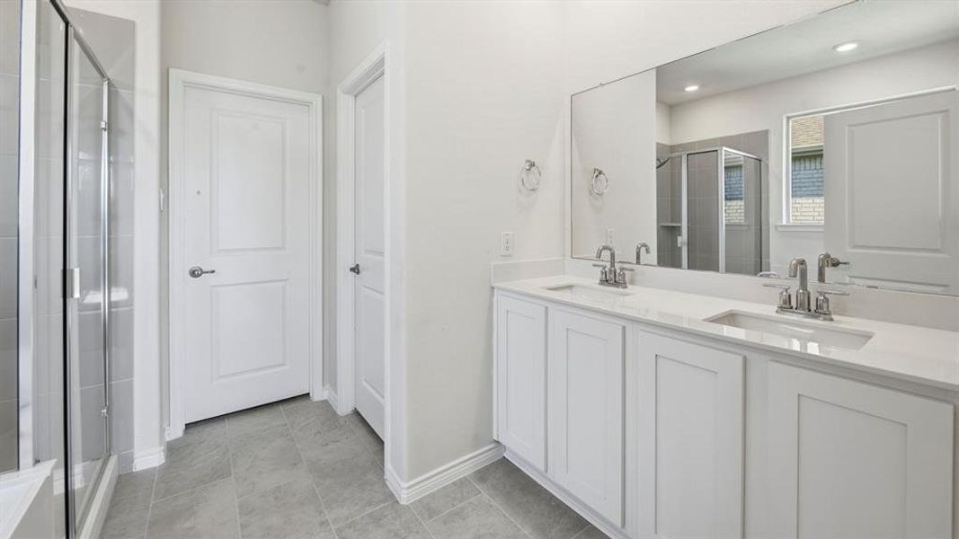 Full bathroom featuring double vanity, a shower stall, and light tile patterned flooring Full bathroom featuring double vanity, a shower stall, and light tile patterned flooring