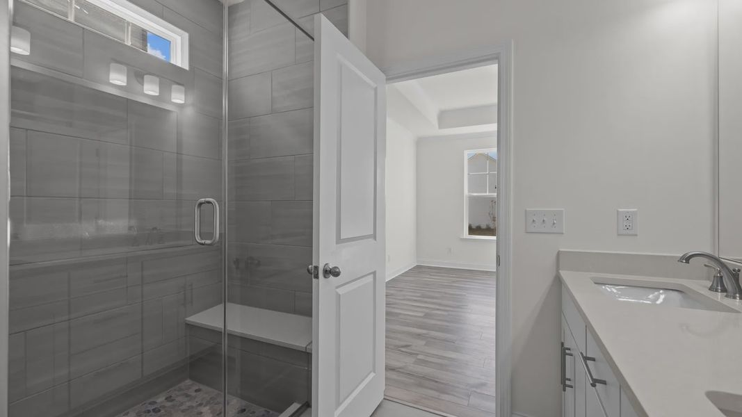 Fairfield primary bathroom with fully-tiled shower with seat and dual-sink vanity, at Lakeside Glen by DRB Homes, York, SC.