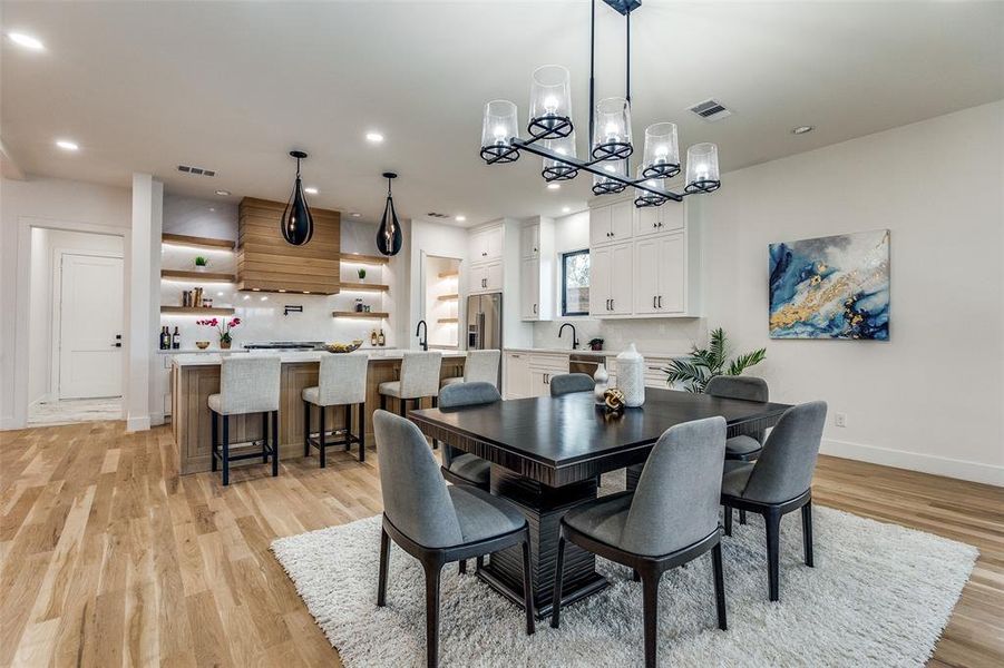 Dining space with light hardwood / wood-style floors, a notable chandelier, and sink