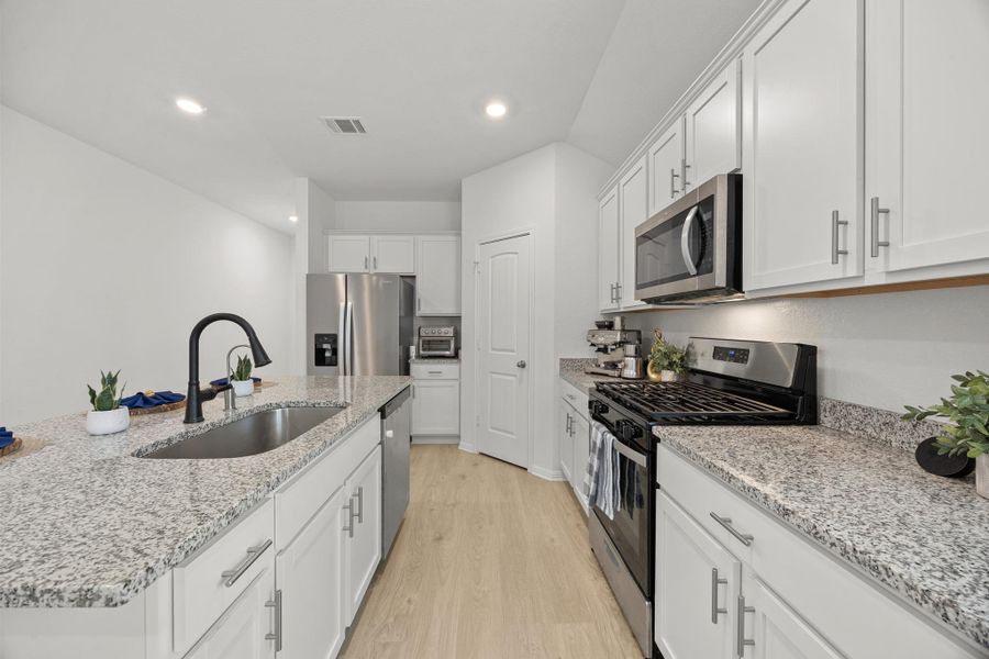 Kitchen with stainless steel appliances, light wood-style floors, light stone counters, and recessed lighting