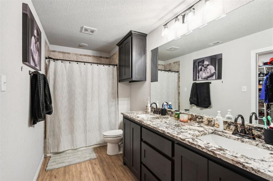 Bathroom featuring hardwood / wood-style floors, a textured ceiling, and walk in shower