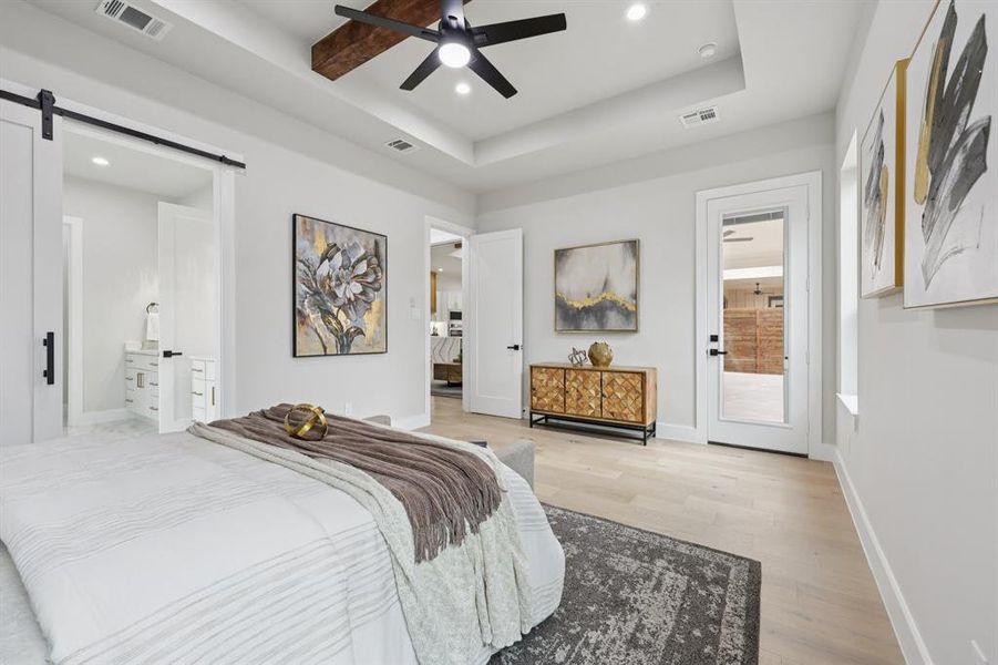 The room features light-colored flooring, a tray ceiling with recessed lighting and a ceiling fan, and a barn door