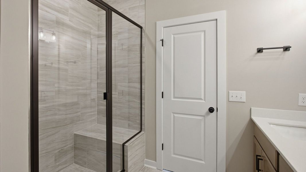 Bathroom with glass enclosed tile shower leading to primary suite Bathroom with glass enclosed tile shower leading to primary suite