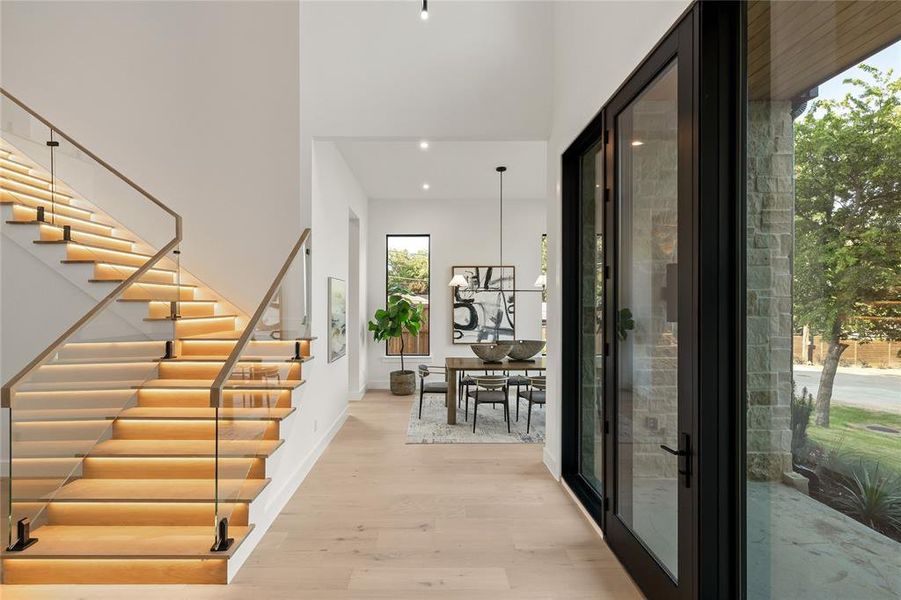Grand entryway featuring a floating staircase with integrated lighting and glass railing Grand entryway featuring a floating staircase with integrated lighting and glass railing