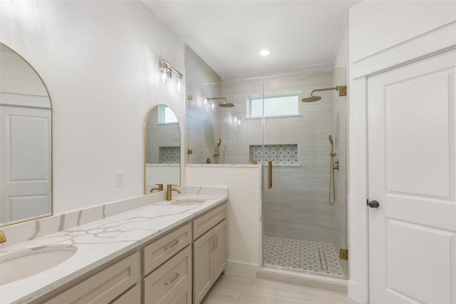 Primary bath has double sink vanity and an elegant shower featuring dual shower heads for a spa-like retreat.