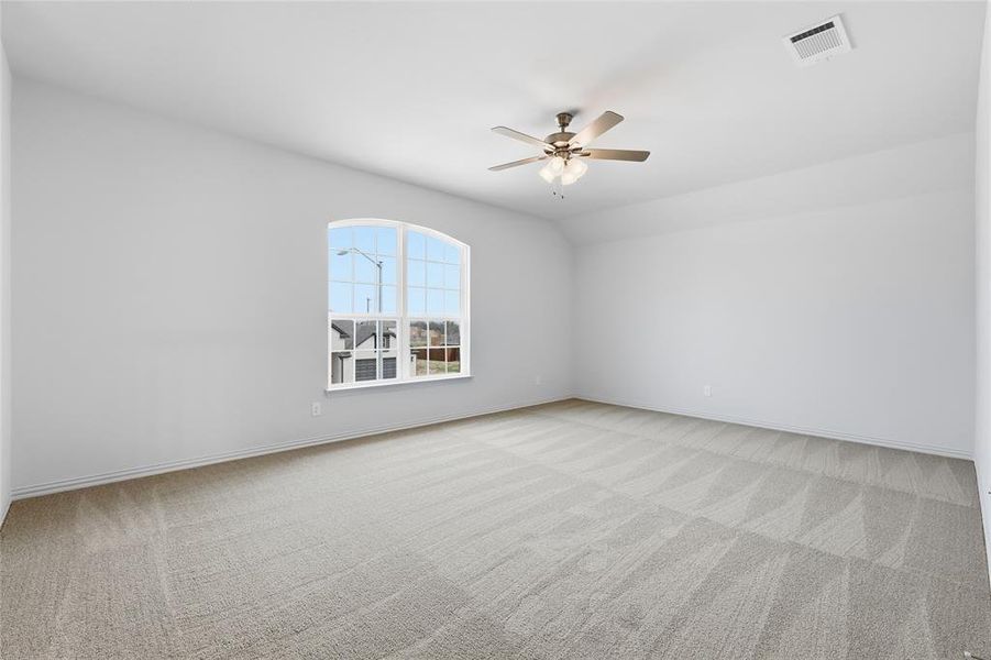 Empty room featuring light carpet, a ceiling fan, and vaulted ceiling