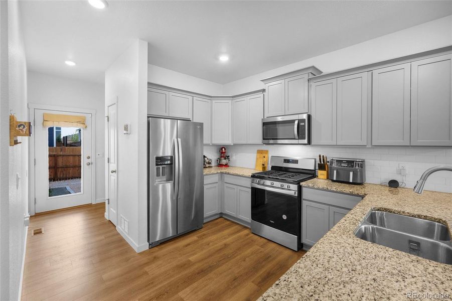 This beautiful kitchen is modern and functional. With a pantry and powder room just down the hall. Access the garage to your left or the private/fenced back yard from the other door.
