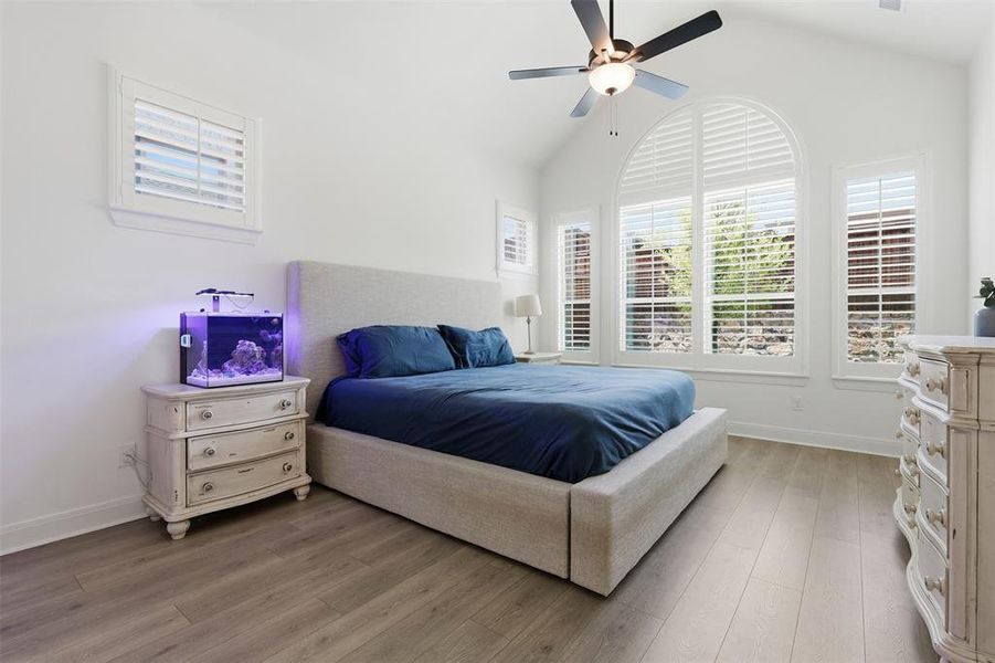 Vaulted ceilings enhance this room featuring wood-finish flooring, white plantation shutters, and a ceiling fan with integrated lighting Vaulted ceilings enhance this room featuring wood-finish flooring, white plantation shutters, and a ceiling fan with integrated lighting