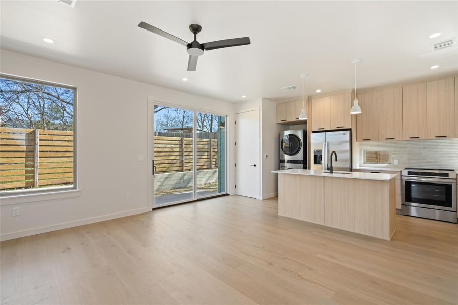 Kitchen featuring visible vents, stacked washer / dryer, modern cabinets, stainless steel appliances, and light brown cabinets