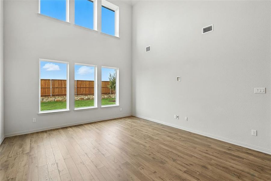 Unfurnished living room featuring wood-type flooring and a towering ceiling