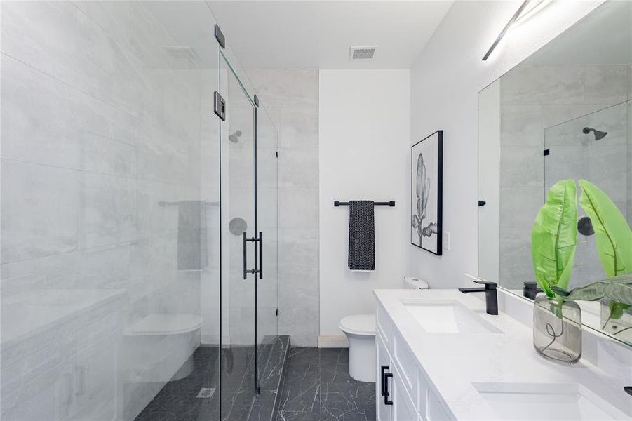 Bathroom with double vanity, a shower stall, and dark marble finish flooring Bathroom with double vanity, a shower stall, and dark marble finish flooring